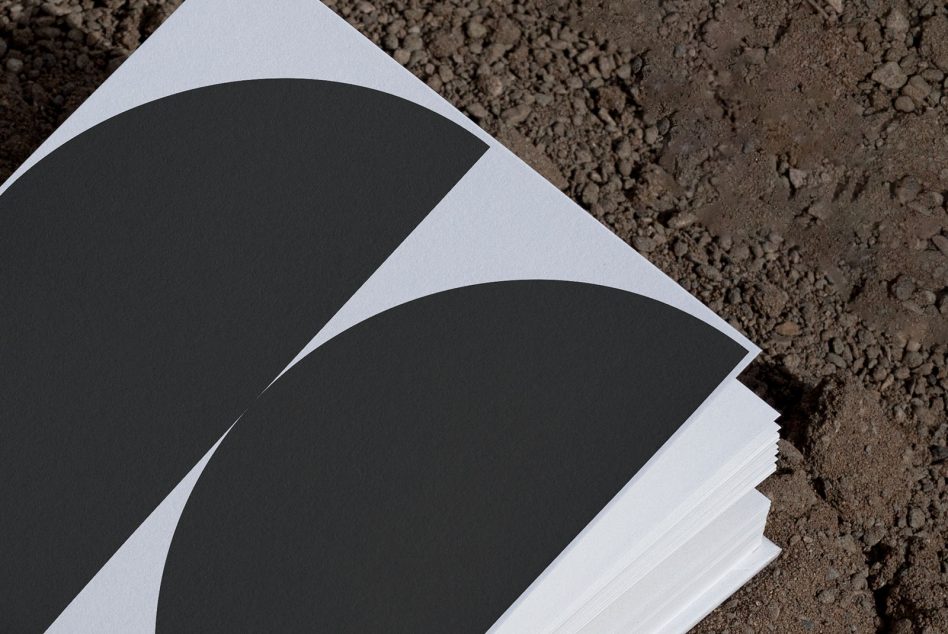 Open spread showing two large black curved shapes on white pages against textured ground