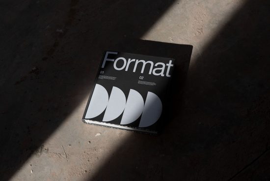 Magazine mockup on concrete floor with dramatic lighting, showcasing modern font and graphic design layout, ideal for presentation.