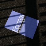 Magazine mockup lying on textured asphalt with contrasting shadows, ideal for presentation, graphic design display.