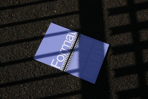 Magazine mockup lying on textured asphalt with contrasting shadows, ideal for presentation, graphic design display.