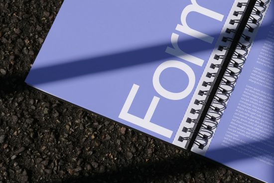 Spiral notebook with modern typography design on textured asphalt, showcasing print mockup and graphic design layout.