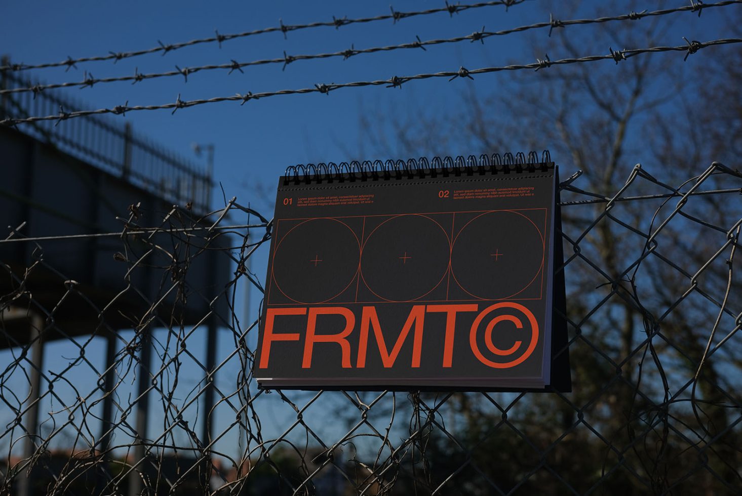 Mockup of designer calendar hung on barbed wire fence, showcasing bold typography and modern layout, perfect for presenting branding projects.