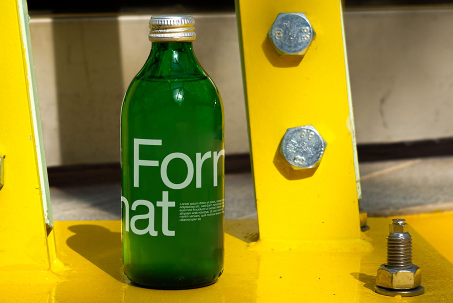 Green bottle mockup with label design on yellow industrial background for branding presentations and graphic design portfolio.