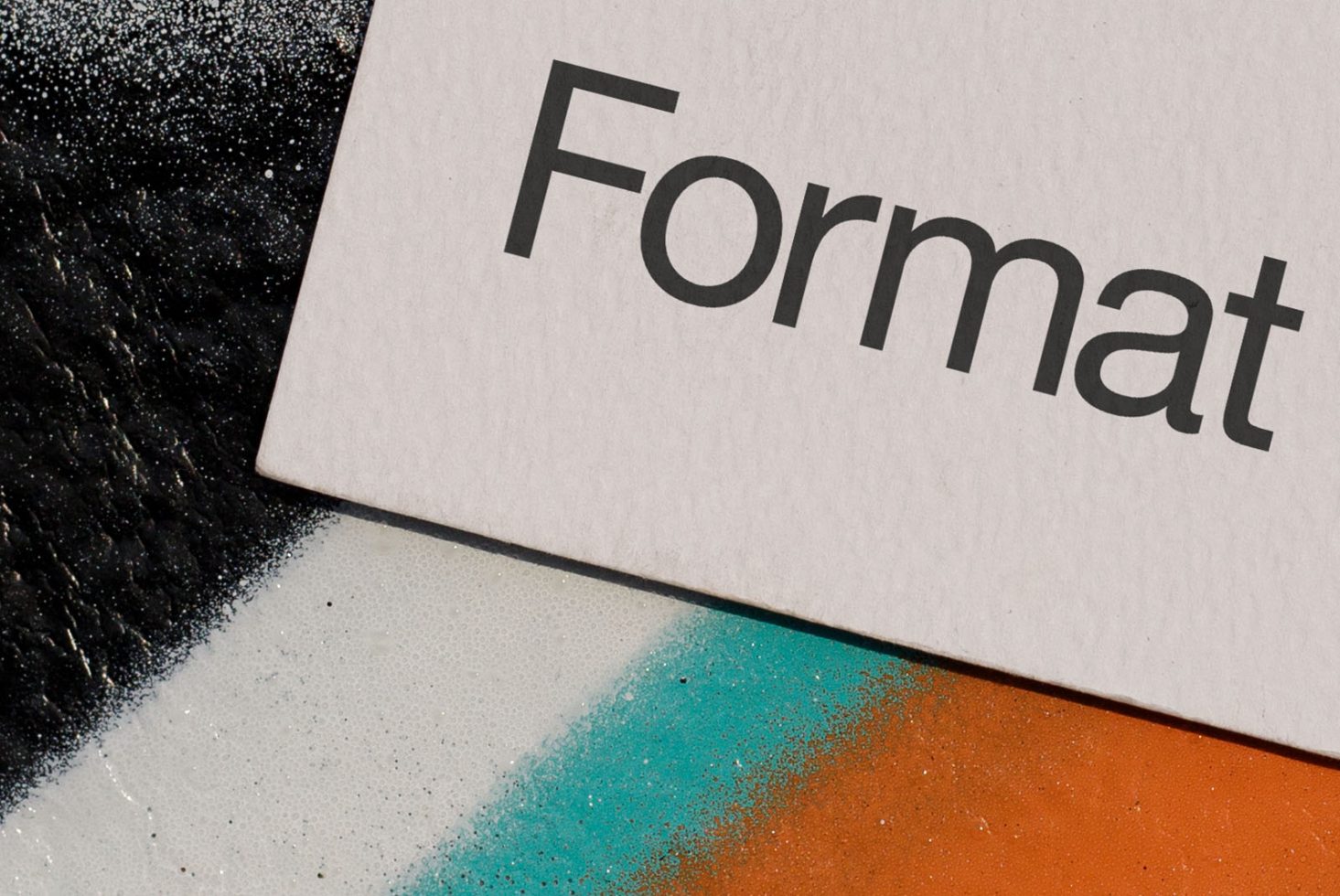 Bold sans-serif font 'Format' on textured paper with colorful paint splatter, ideal for mockup, graphic design, and typography projects.