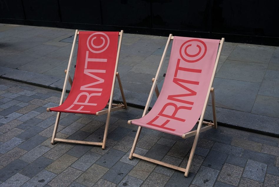 Two striped deck chairs on concrete ground with smiley face logo, sitting outdoors