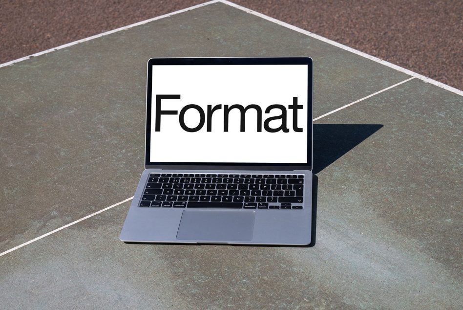 Silver laptop on textured pavement showing word on display with sharp shadow cast