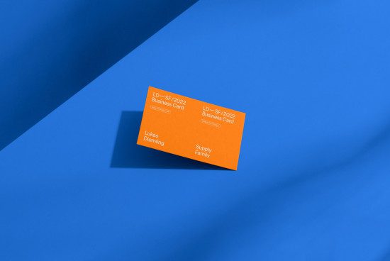 Orange business card mockup with shadow on blue background, showcasing modern design, perfect for graphic designers presentations and templates.