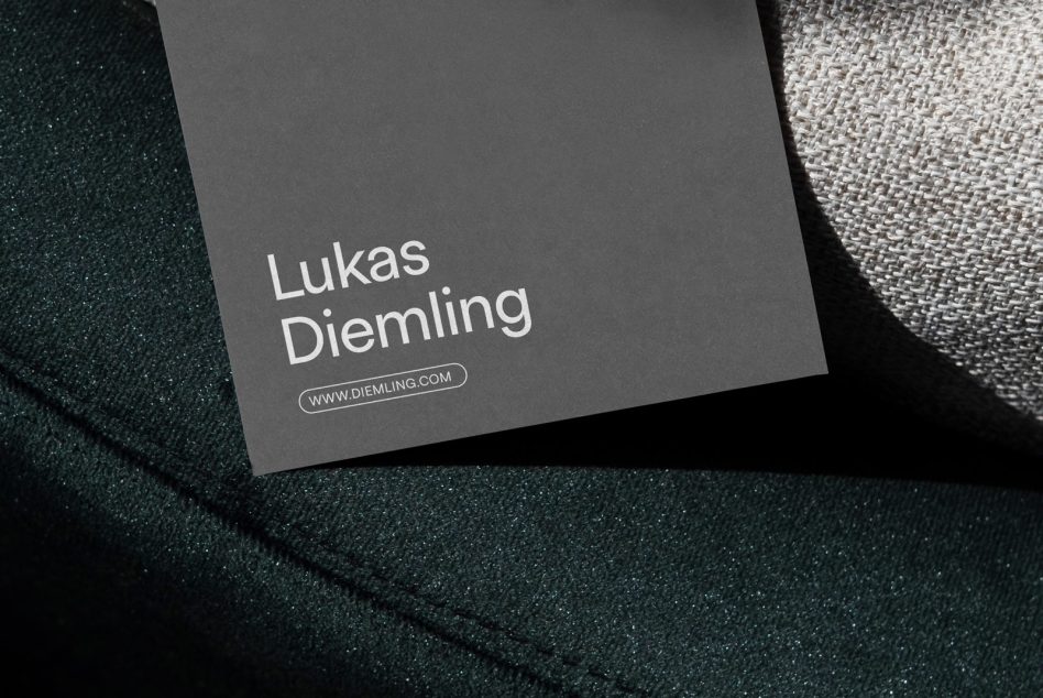 Dark gray business card with white typography for Lukas Diemling resting on textured fabrics
