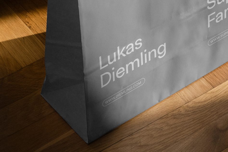 Paper shopping bag mockup with realistic shadows on a wooden floor, showcasing custom branding design for designer portfolio.