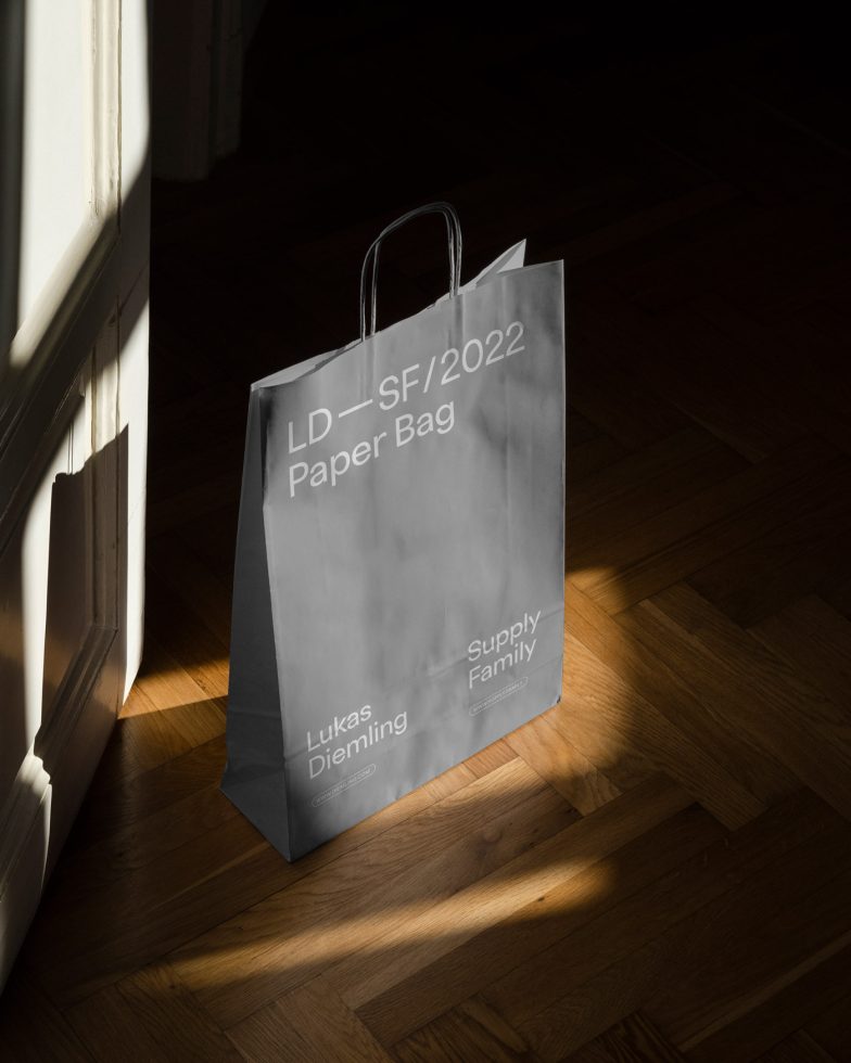 Elegant paper bag mockup in sunlight on wooden floor, realistic branding packaging design, photorealistic shadow detail, designer asset.