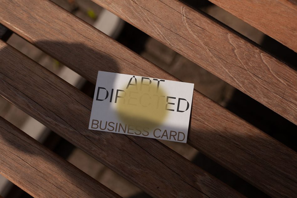 Business card lying on wooden slats with yellow overlay shadow from window light