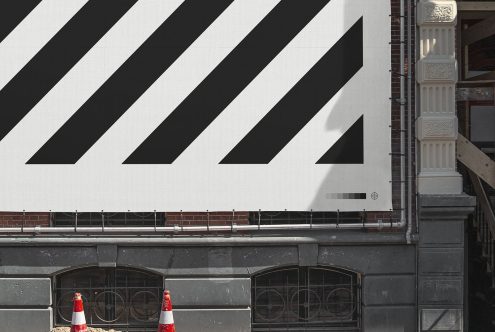 Urban billboard mockup on a brick building exterior for outdoor advertising design presentation, clear sky, city environment. Graphic designers asset.