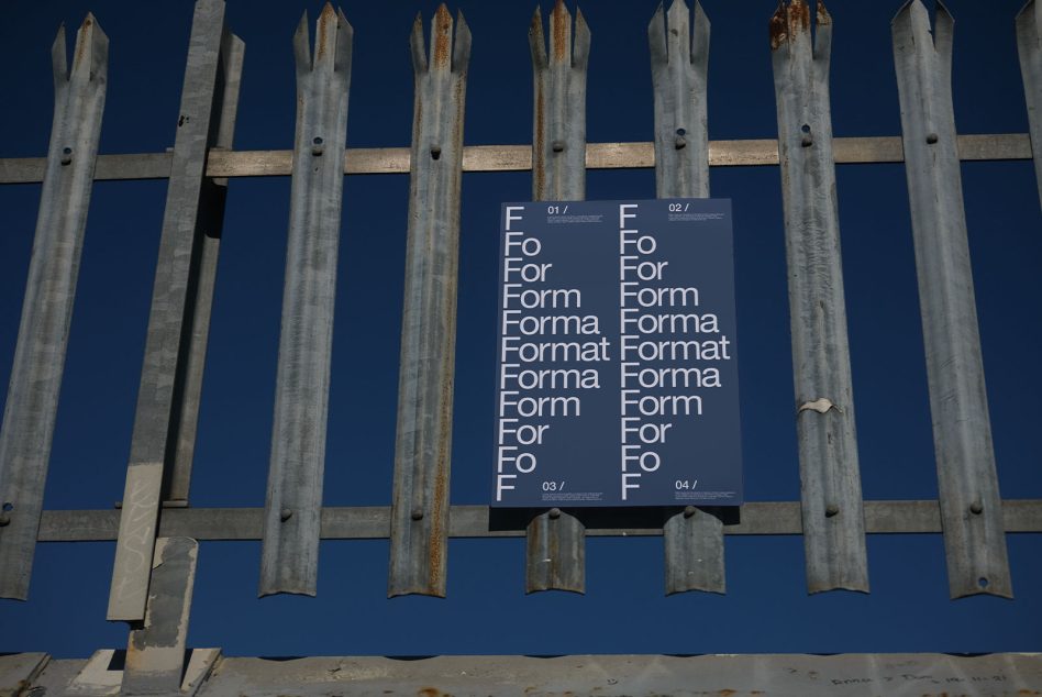 Alt: Typography showcase with various fonts on a poster behind a metal fence under a clear blue sky, ideal for Graphic Design inspiration.