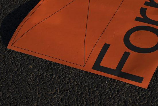 Orange poster with bold black typography partly visible, lying on a textured asphalt surface, ideal for mockup and design presentations.