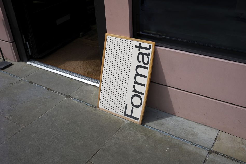 Wooden framed sign leaning against pink storefront, text reads 'Format' in large sans-serif