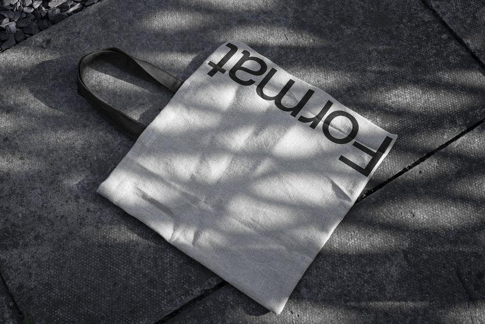 Canvas tote bag mockup with shadows on textured pavement, suitable for showcasing design and font work for designers.