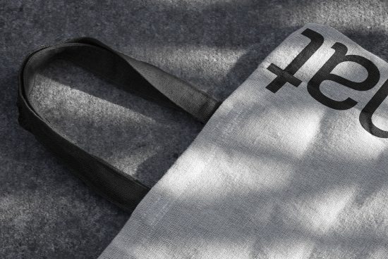 Close-up of a tote bag on textured background with bold typography, ideal for mockup designs, texture overlays, and product presentations for designers.