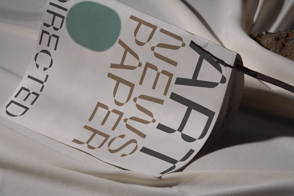 Tilted paper mockup showing serif typography with teal circle on canvas fabric surface