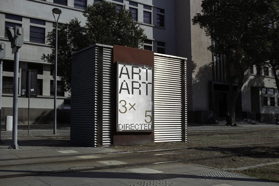 Modern public kiosk mockup with striped metal panels, urban plaza setting with trees
