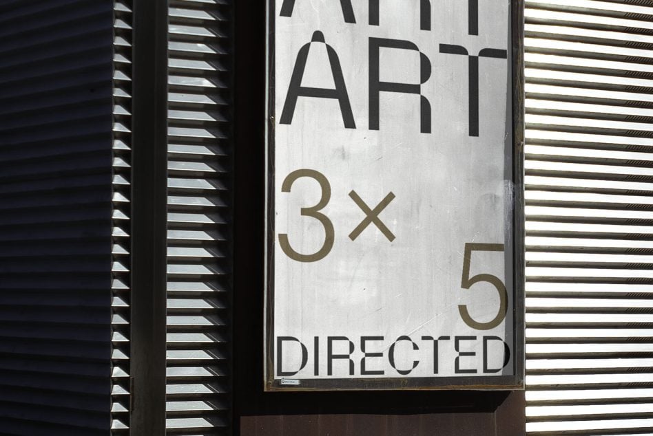 Vertical street sign mockup between metal shutters showing text layout on weathered surface
