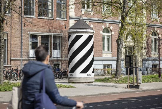 Urban mockup of a cylindrical advertisement column with black and white stripes, suitable for showcasing graphic designs or posters.