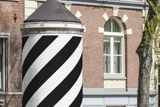 Urban tower wrapped in black and white diagonal stripes, contrasting traditional brick building, clear day. Perfect for mockup graphics, urban designs.