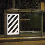 Nighttime bus stop with illuminated blank billboard mockup, urban setting, ready for advertising design, clear poster space.