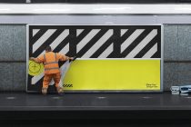 Construction worker applying striped design to yellow barrier wall