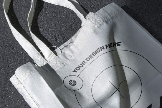 White tote bag mockup with customizable design area on asphalt background, ideal for presentations and branding projects.