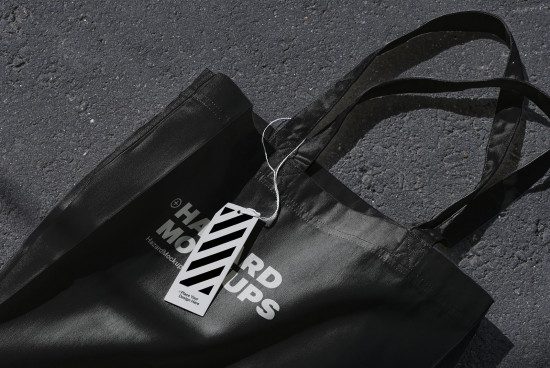 Black tote bag mockup with hang tag on asphalt background, realistic branding presentation tool, tote bag design mockup for designers.