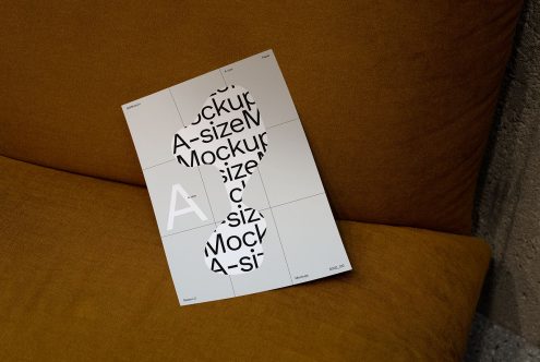 A4 paper mockup with typographic design, resting on a textured brown couch, ideal for presenting print templates and fonts to designers.