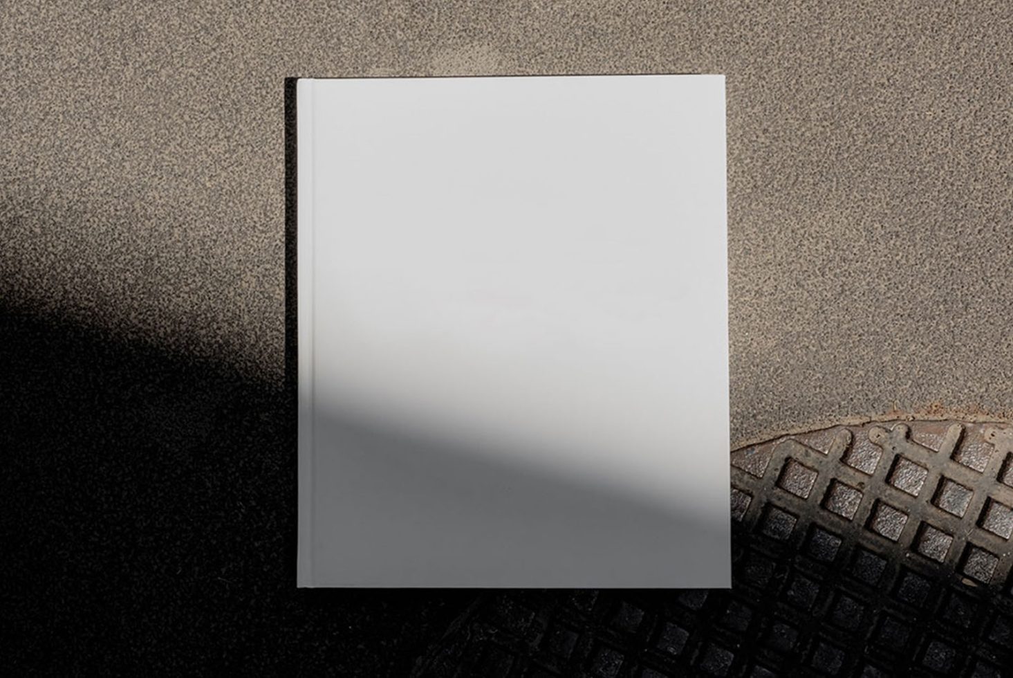 Blank book cover mockup on textured background with shadow, perfect for designers to display cover designs.