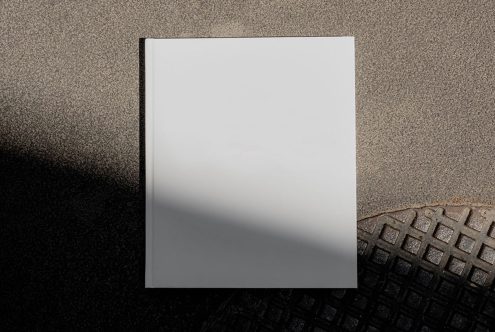 Blank book cover mockup on textured background with shadow, perfect for designers to display cover designs.