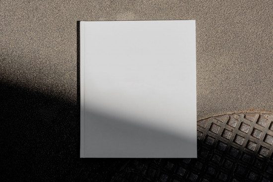 Blank book cover mockup on textured background with shadow, perfect for designers to display cover designs.