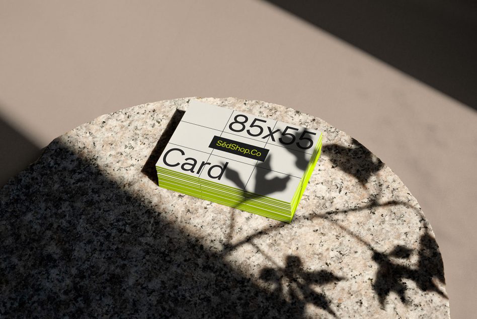 Card stack with neon green edge detail on round concrete stone in daylight
