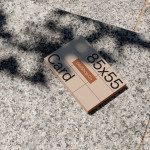 Business card mockup laying on textured sidewalk in sunlight creating shadows, ideal for presenting designs to clients.