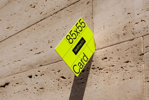 Yellow business card mockup with shadows on a textured concrete wall, showcasing design and dimensions for graphic designers.