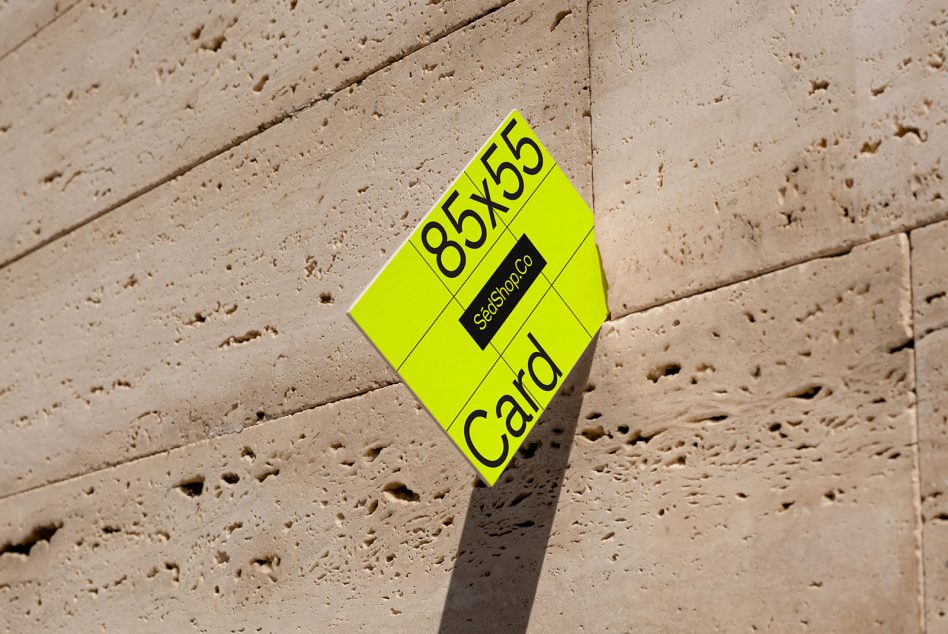 Business card mockup in neon yellow tilted on travertine texture with sharp shadow