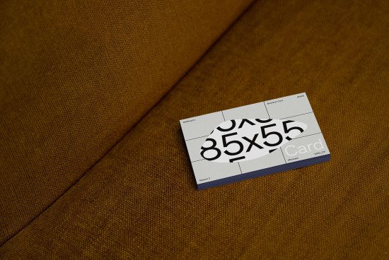 Business card mockup with trendy typography design on textured mustard fabric surface, ideal for designers' presentation needs.