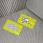 Business card mockup on textured couch with bright yellow design and bold typography, ideal for realistic presentation and portfolio display.