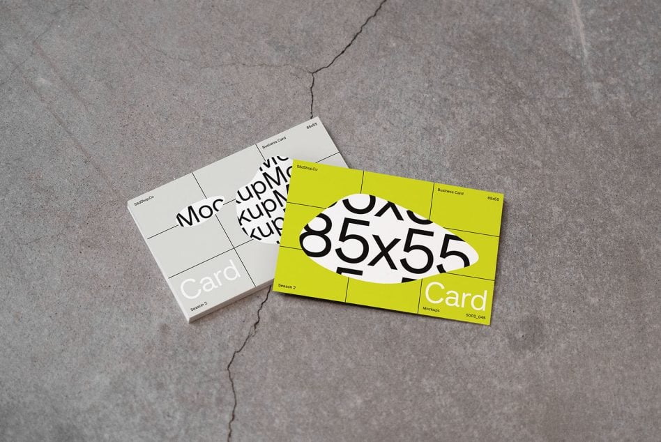 Lime green business card mockup with bold numbers beside cream white card on concrete surface outdoors