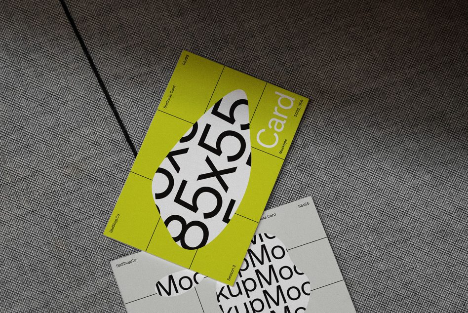 Neon yellow folded card mockup displaying oversized numerals with cream colored cards beneath on grey fabric