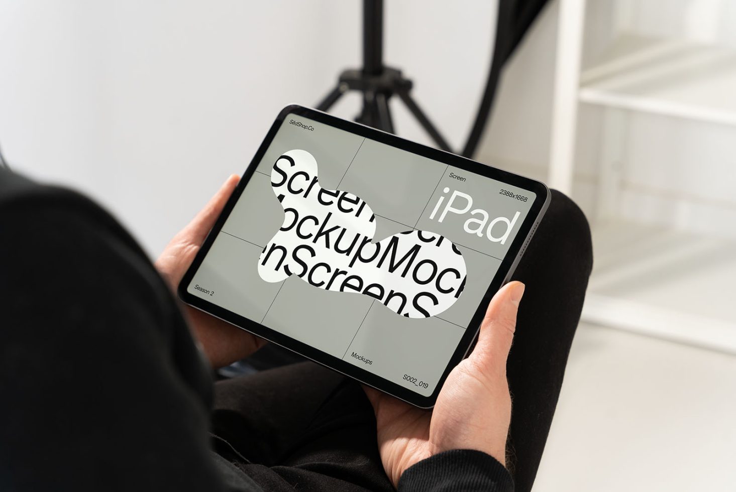 Person holding an iPad displaying mockup screens, ideal for designers looking to present digital designs in a professional mockup template.