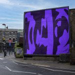 Urban billboard mockup with abstract purple design on city street background, perfect for posters, ads showcasing in a realistic setting for designers.