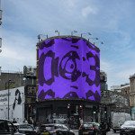 Urban billboard mockup with bold purple abstract design, showcased on a city street corner, with cars and pedestrians for realistic setting.