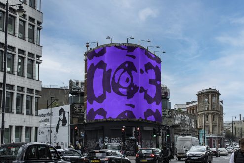 Urban billboard mockup with bold purple abstract design, showcased on a city street corner, with cars and pedestrians for realistic setting.