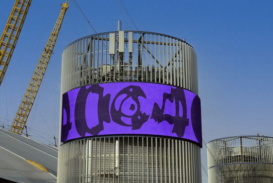 Urban billboard mockup on cylindrical building with vibrant purple graffiti-style design, clear sky, suitable for advertising and branding presentations.