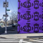 Urban street view with a vibrant purple graffiti wall, ideal for mockup background, featuring street signs, cityscape, and clear sky.