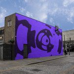 Urban street wall with vibrant purple abstract mural for mockup designs, showcasing street-art style graphics, ideal background for display.