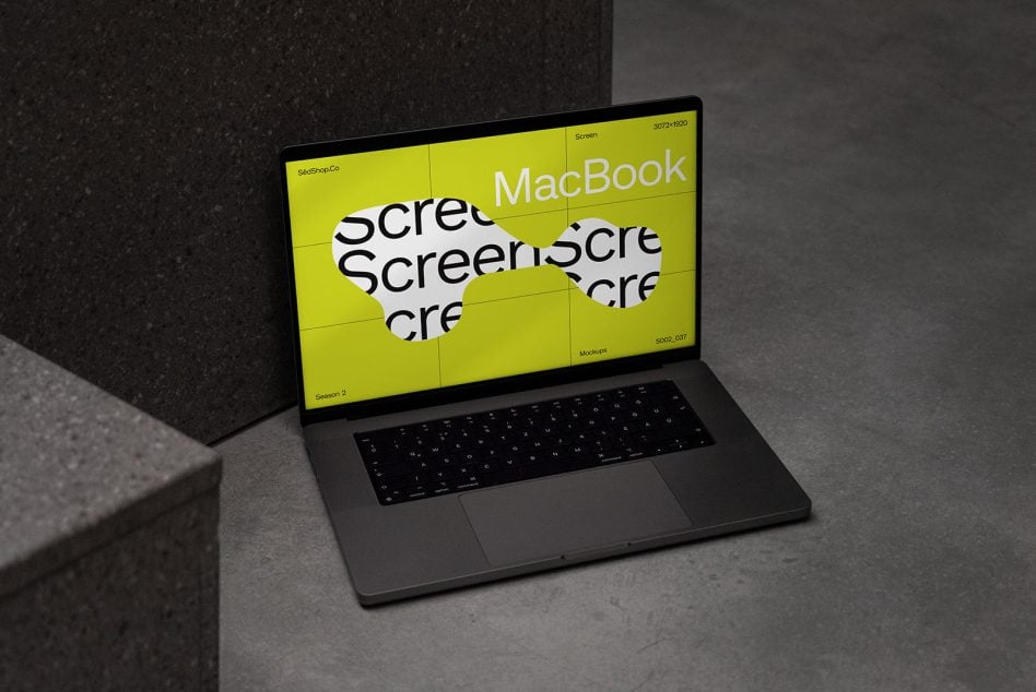 Full MacBook laptop mockup showing neon yellow screen with geometric cutouts in minimal workspace setting